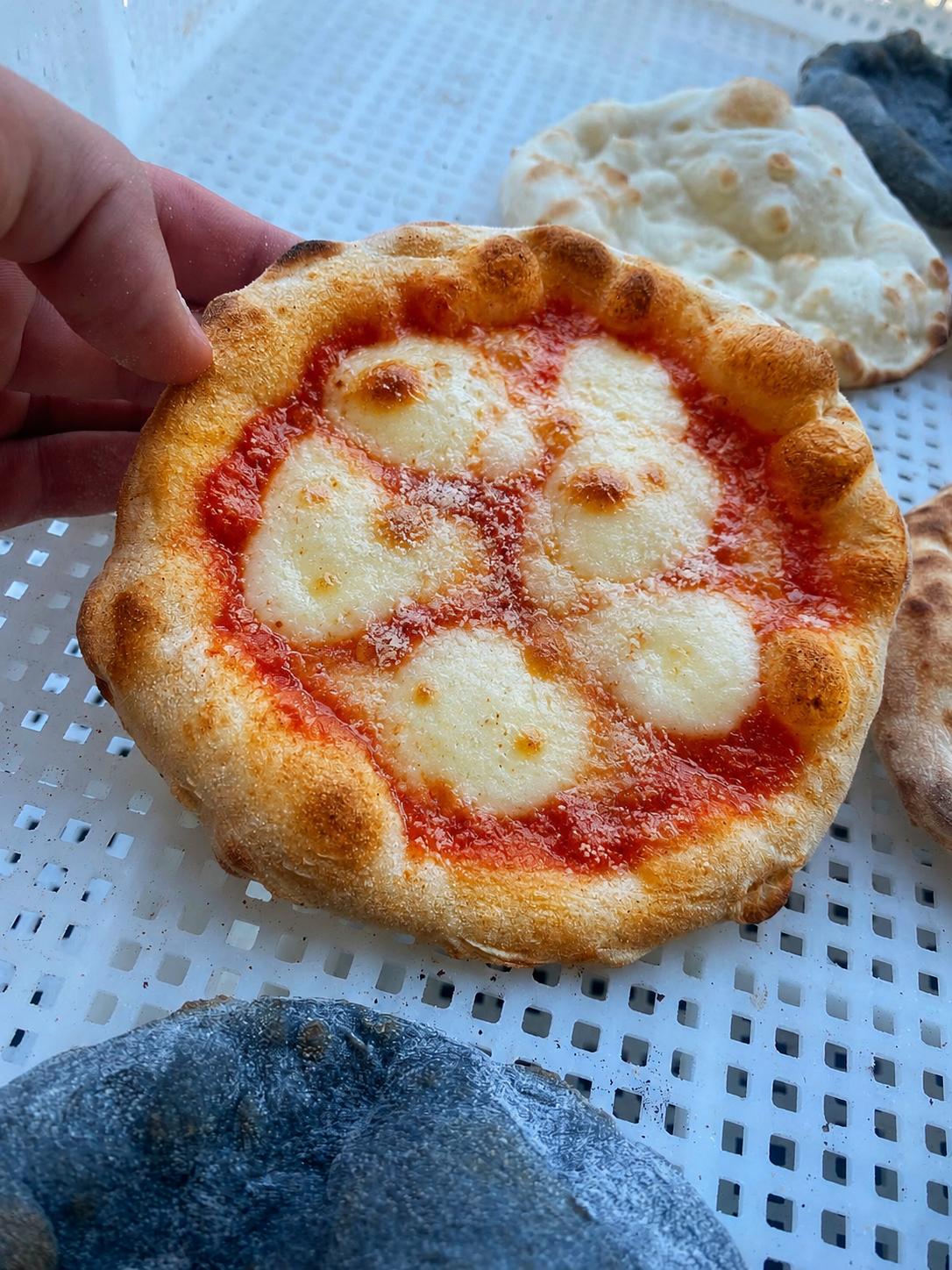 13 cm wood-fired margherita mini pizza held in one hand